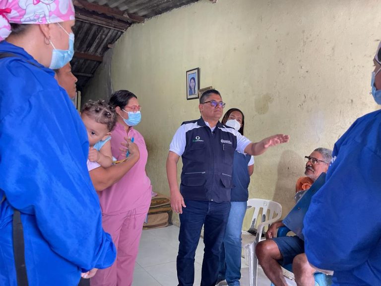 Secretario de salud y personal de salud hablando con habitantes dentro de una casa