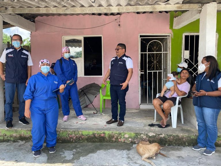 Secretario de salud, funcionarios y dos caminantes de salud en terraza de vivienda con señora con bebé