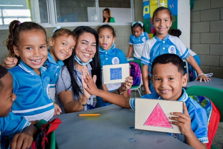 Niños de preescolar con docente en escritorio