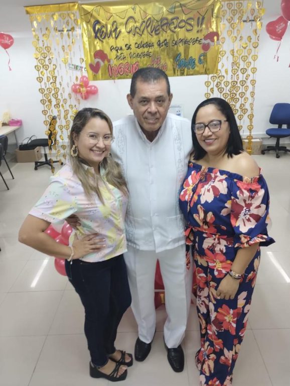 Un hombre y dos mujeres en celebración de cumpleaños con decoración roja y dorada