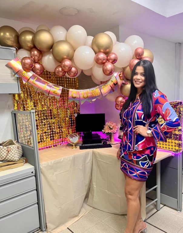 mujer de pie en su escritorio decorado con globos dorados, oro rosa y beige