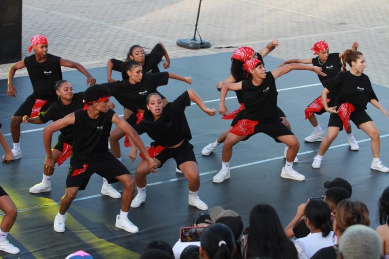 Grupo de jóvenes bailando vestidos con licras y camisetas negras con rojo