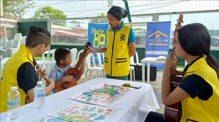 Niño tocando guitarra frente a funcionarios en feria de servicios