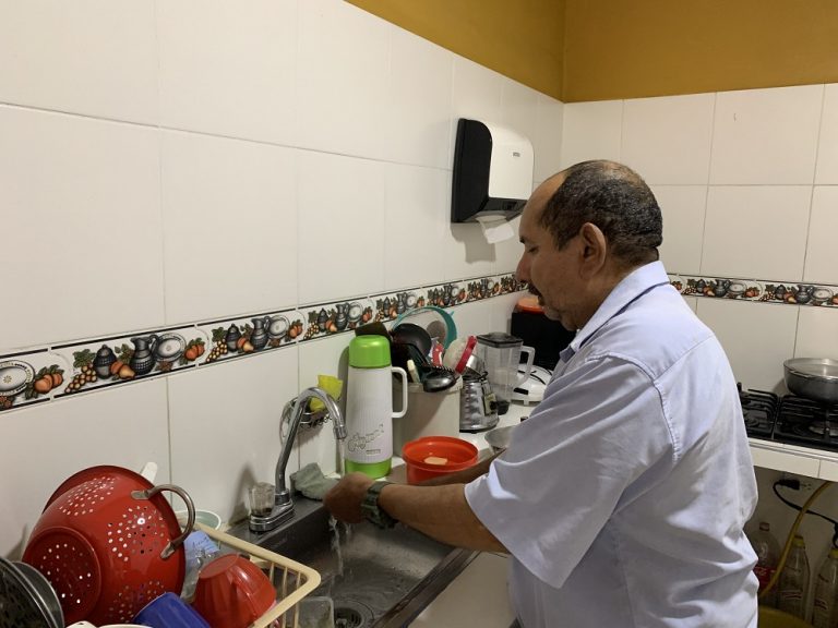 Señor abriendo la llave del lavaplatos en su cocina