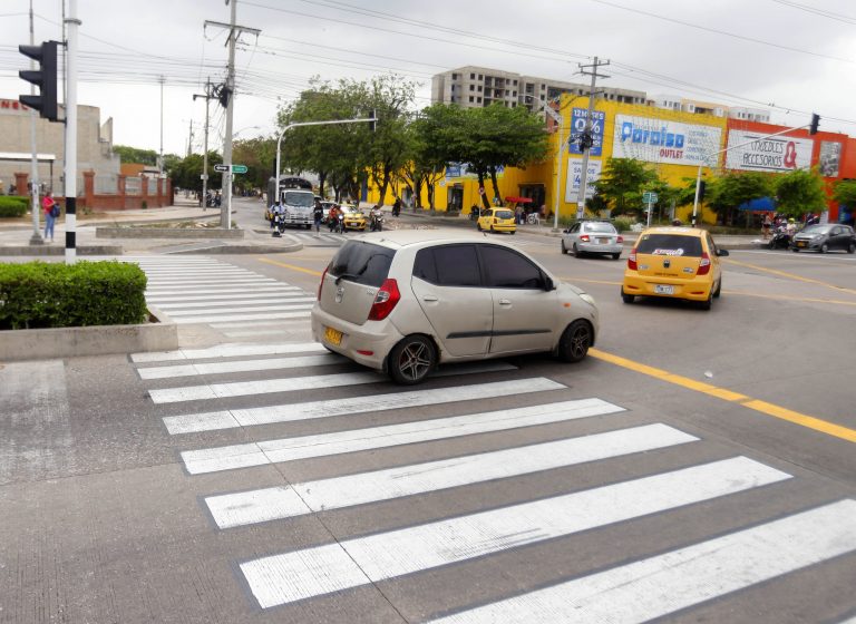 Vía con cebra pintada para paso de peatón y carro pisando la cebra