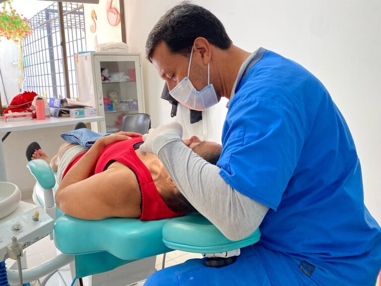 Profesional de la salud atendiendo a paciente en mesa de odontología.