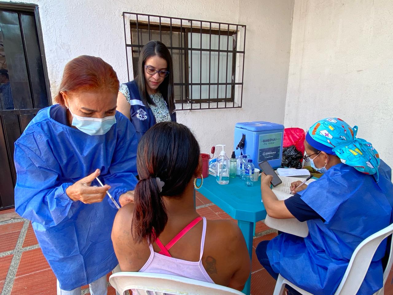 Profesionales de la salud vacunando a beneficiaria.