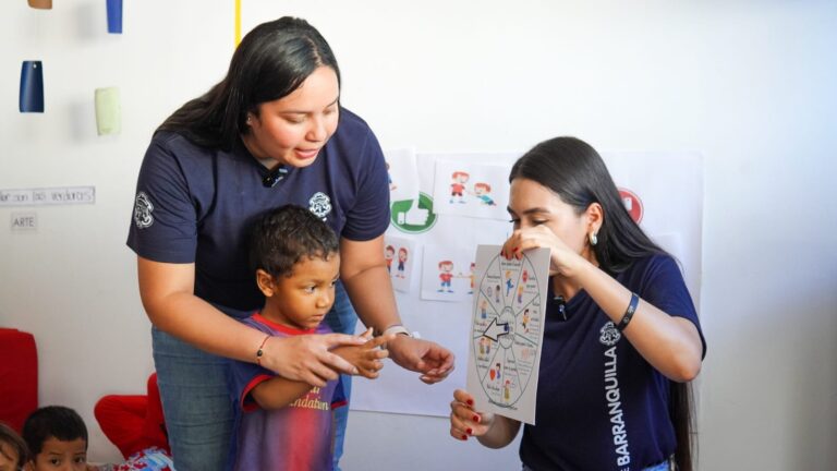 Dos funcionarias de la alcaldía enseñan a leer a una niña.