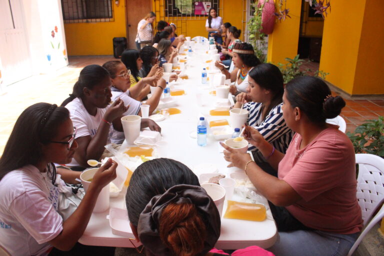 Mujeres migrantes comiendo en una mesa