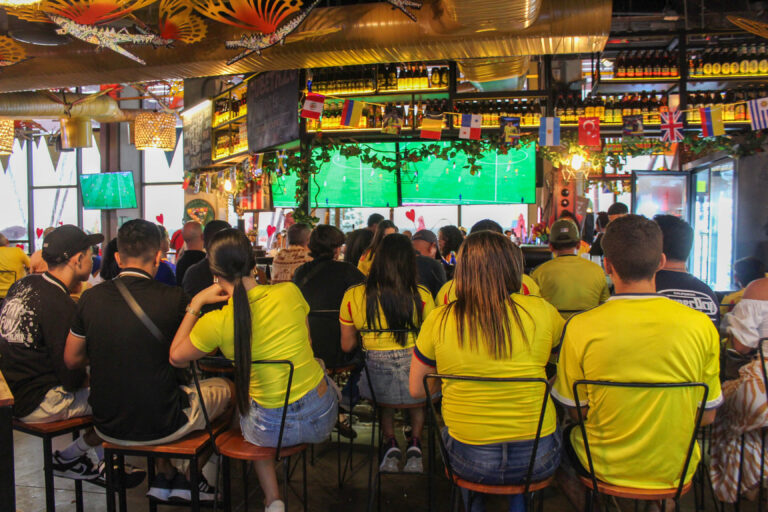 Grupo de personas viendo partido de fútbol en pantallas