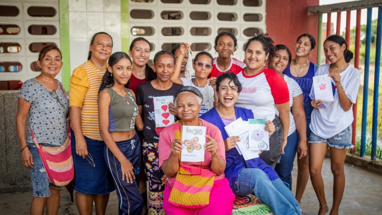 Mujeres y formadora levantando tarjetas, simbolizando apoyo y trabajo en equipo.