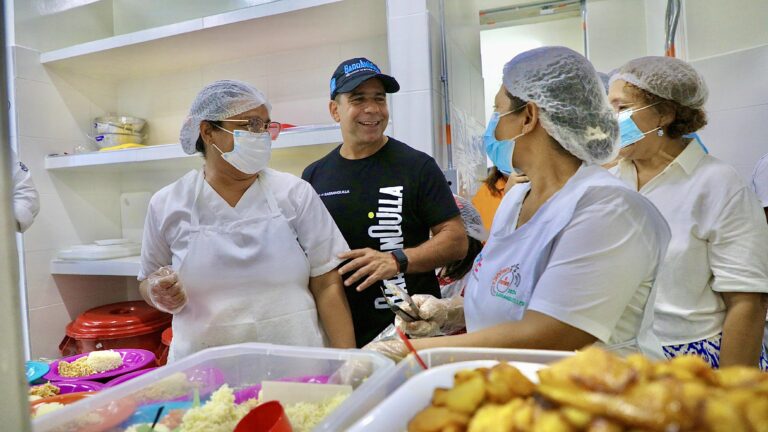 El Alcalde Char y mujeres preparan comida en el comedor de un colegio.