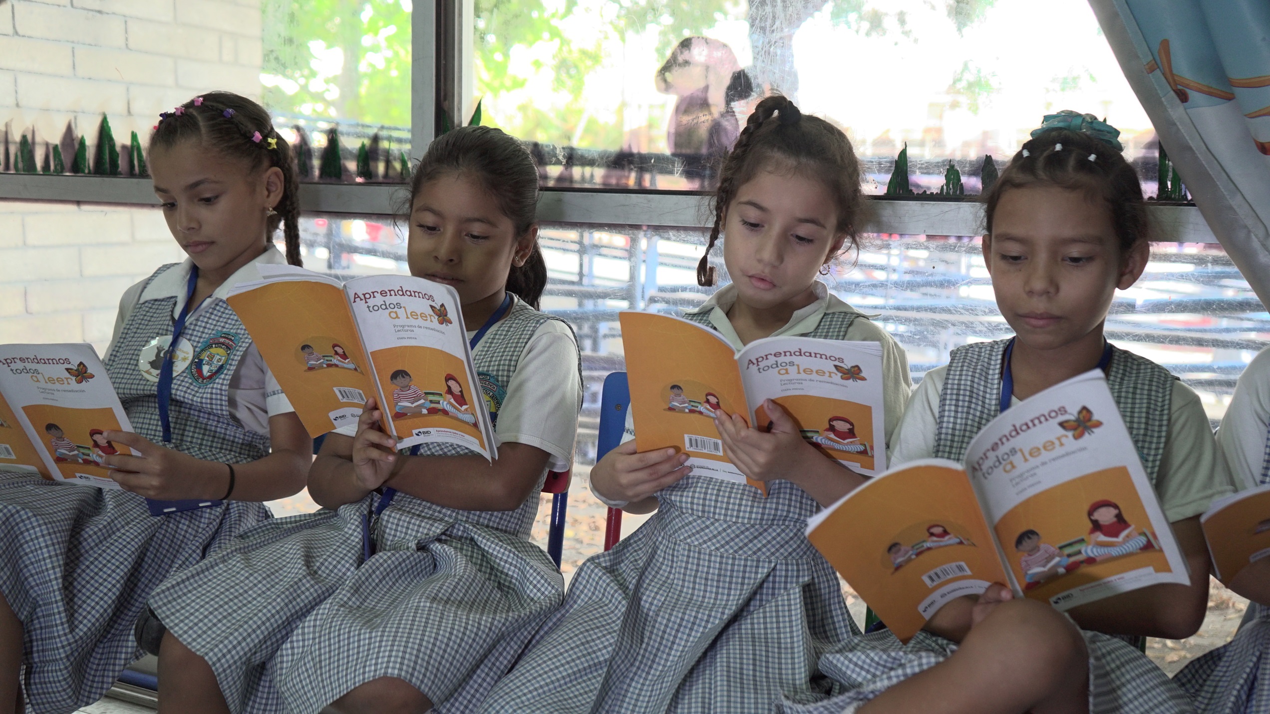 Grupo de niñas leyendo libros en el aula de clases.