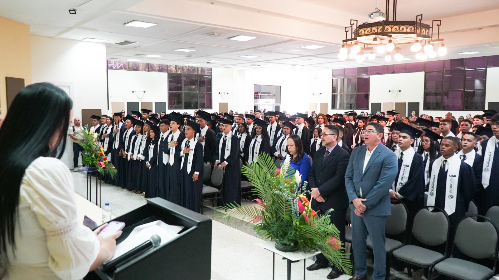 Jóvenes graduados de carreras profesionales reunidos en auditorio.