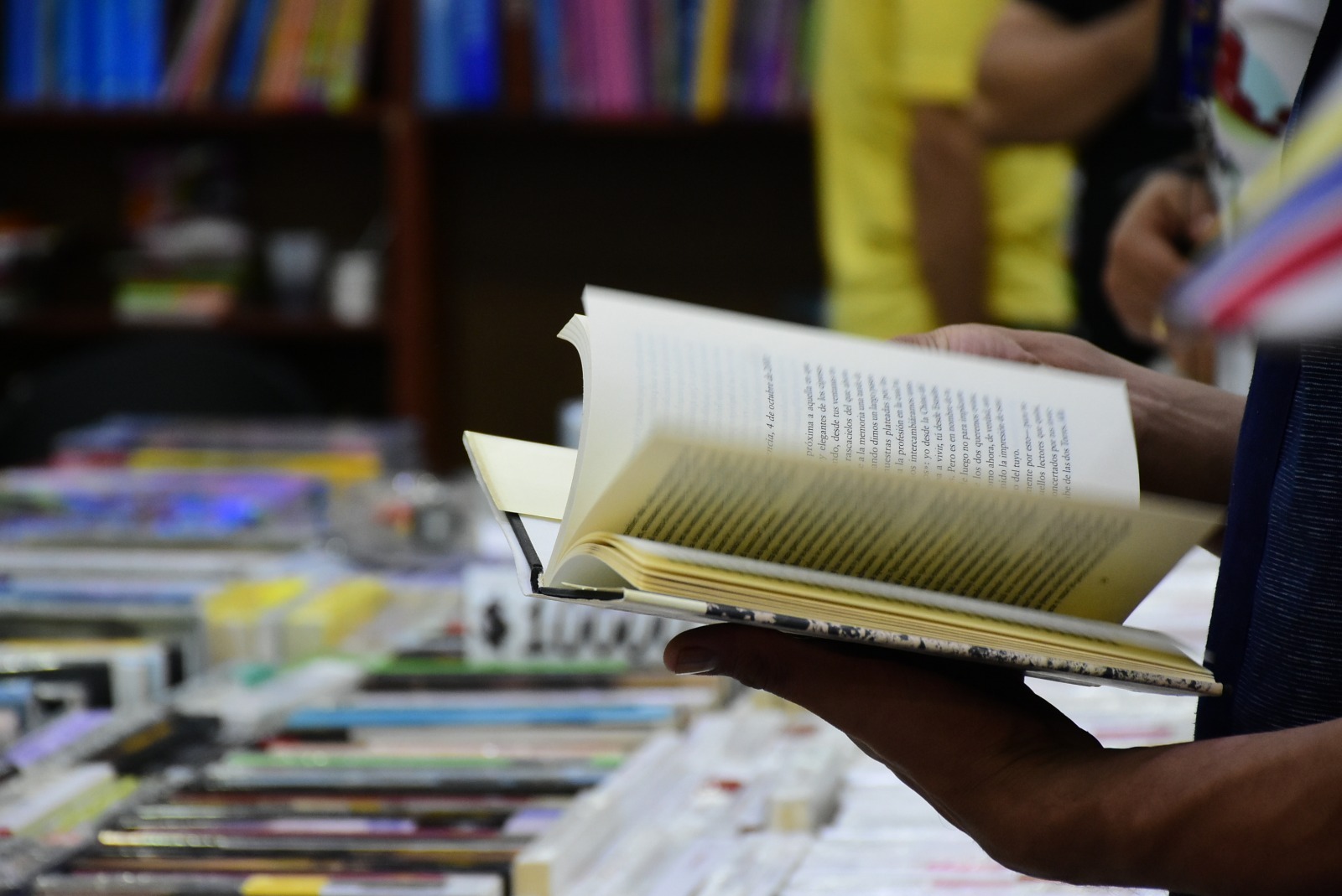 Persona sosteniendo un libro abierto frente a una mesa.