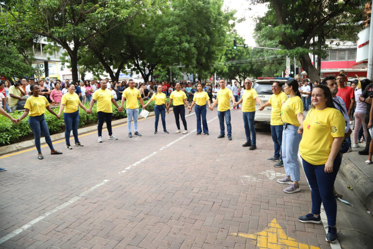 Funcionarios Alcaldía de Barranquilla, formando un círculo de manos unidas en la calle.