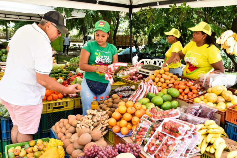 Personas comprando frutas y verduras en un "A tu barrio mercado"