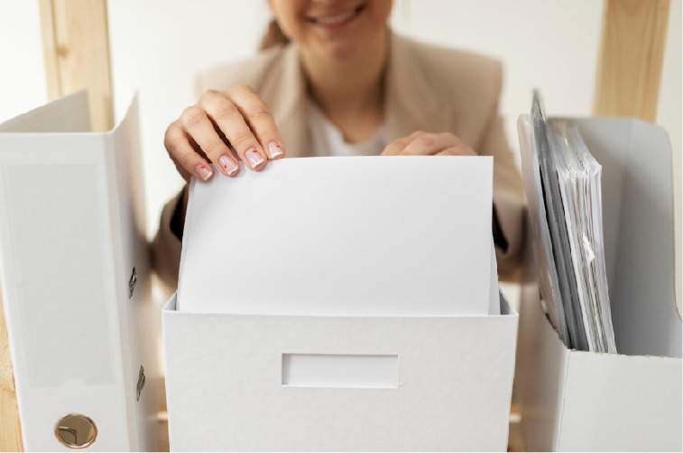 Mujer con una carpeta en la mano, sonriendo, simbolizando éxito y positividad en su entorno laboral.