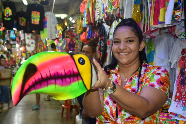 Mujer comerciante sosteniendo máscara de tucán.