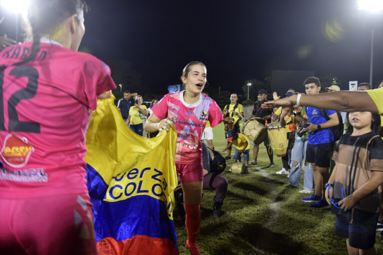 Jugadoras celebran triunfo con bandera de Colombia en el estadio