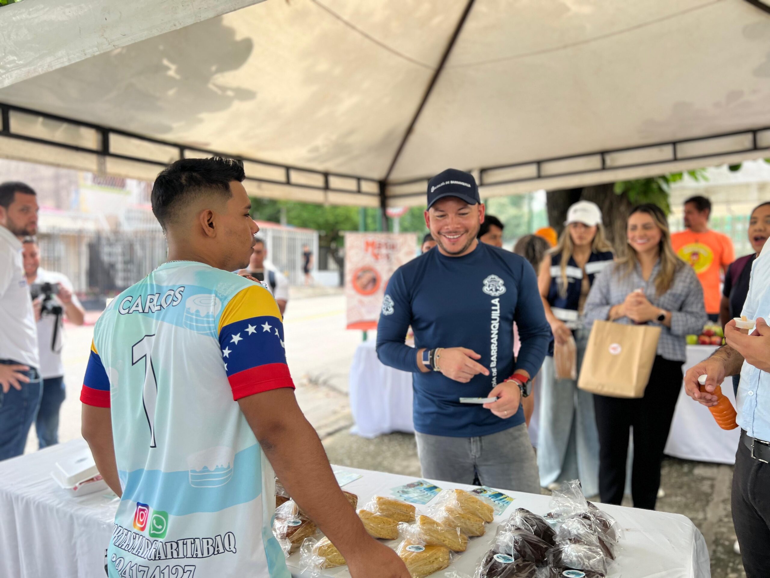 Nelsón Patrón junto con migrante emprendedor en feria.