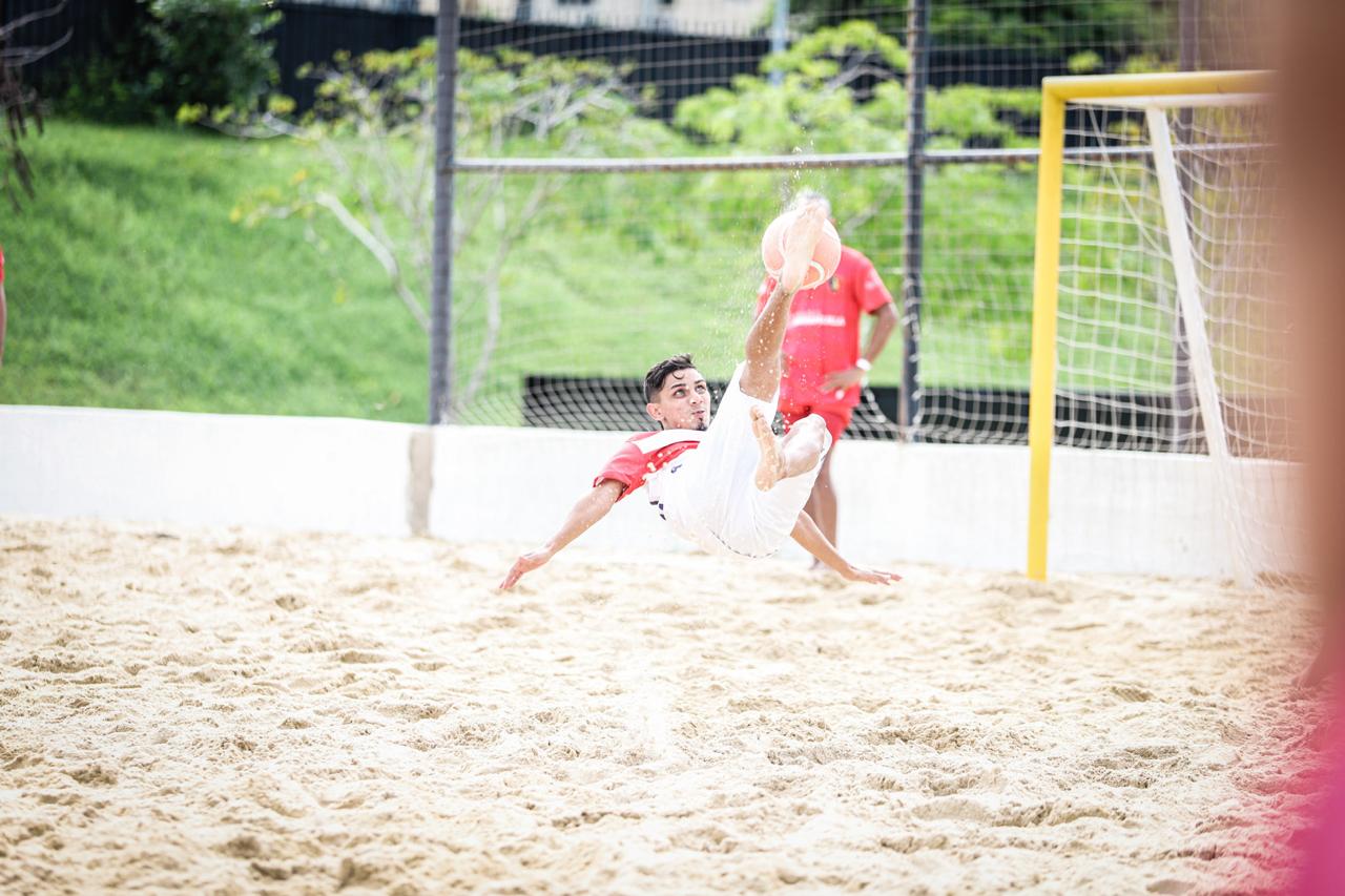 Jugador de fútbol playa en salto en el aire.