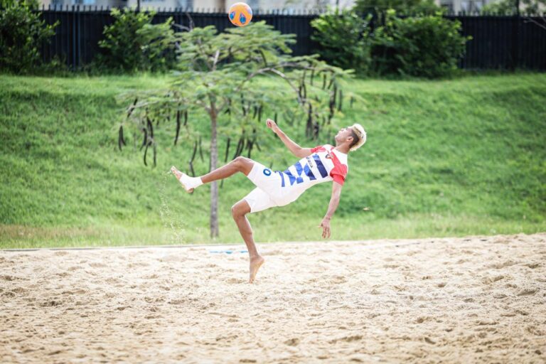 Jugador de fútbol playa en salto en el aire.