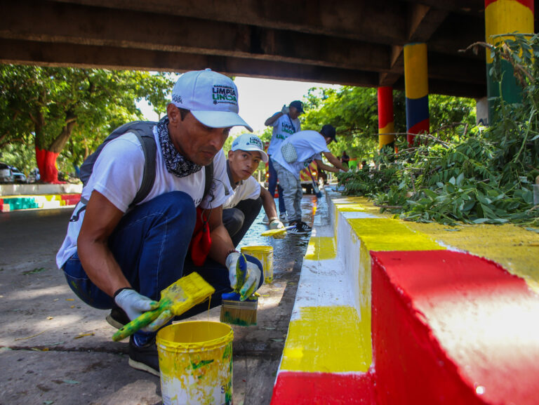 Voluntarios pintan aceras debajo de un puente