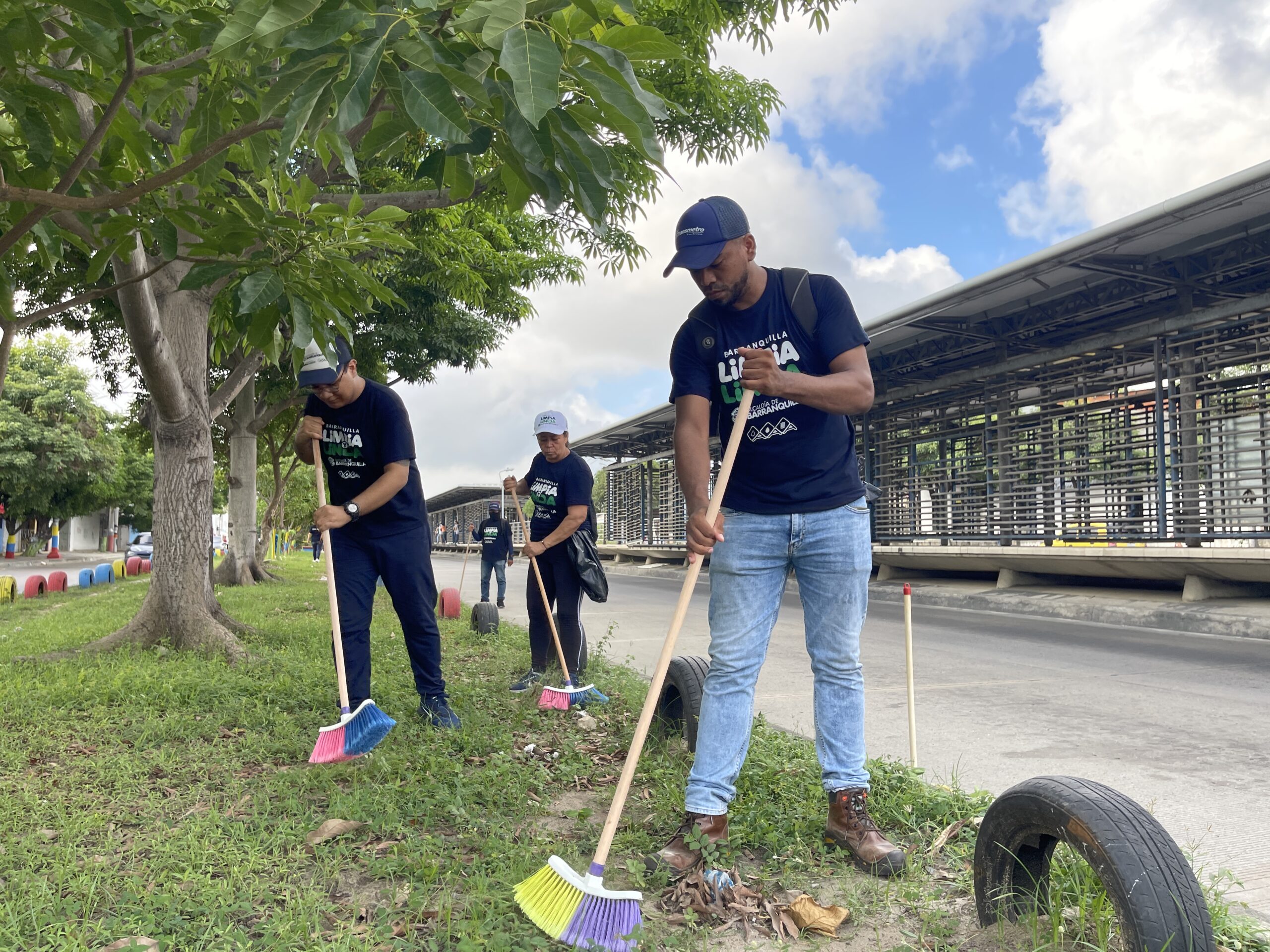 Funcionarios barriendo zona verde cerca a estación de Transmetro