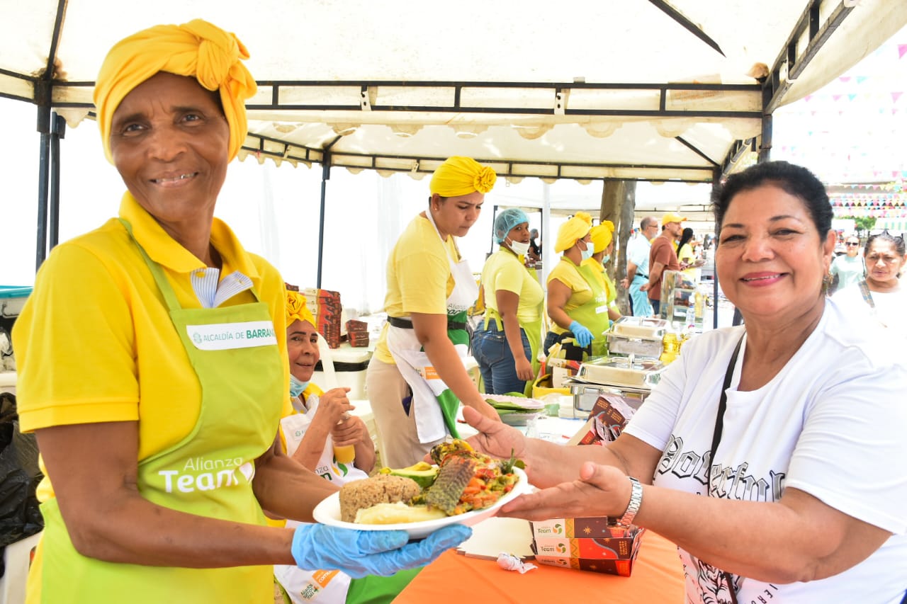 Cocinera entrega platos a comensales durante el evento Sabor Bajero.