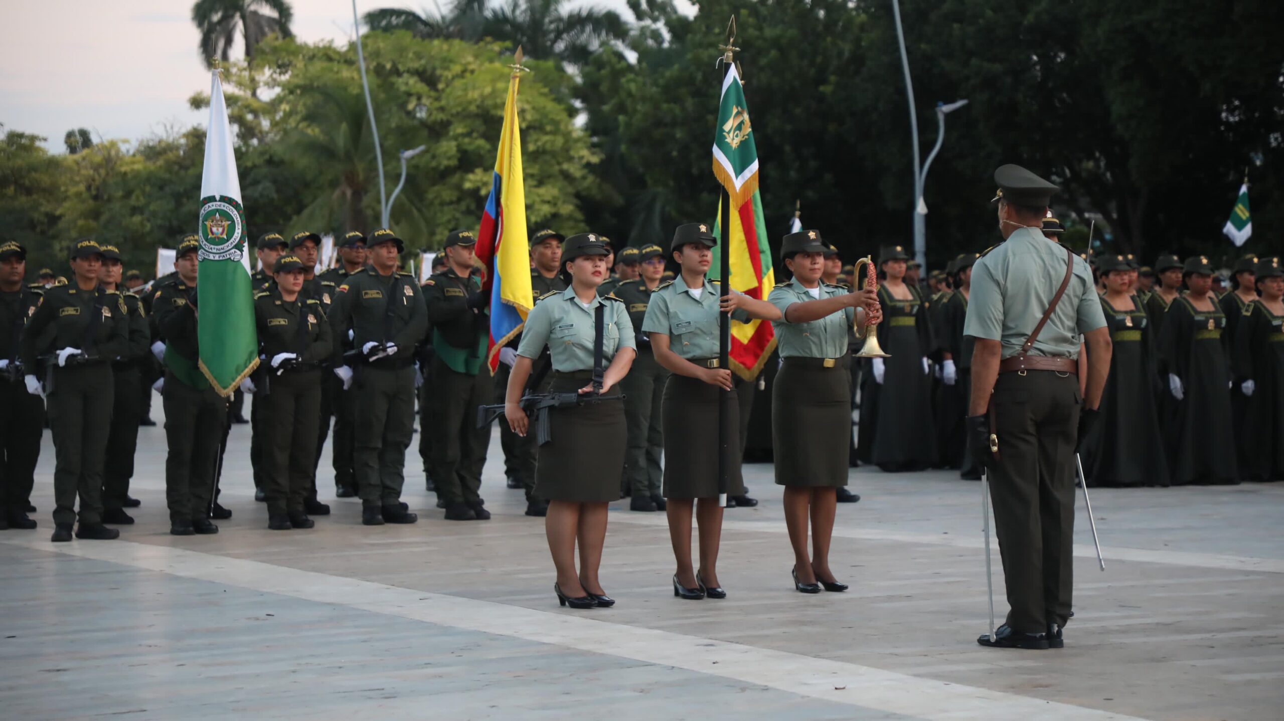 Grupo de policías en posición firme, portando banderas institucionales.