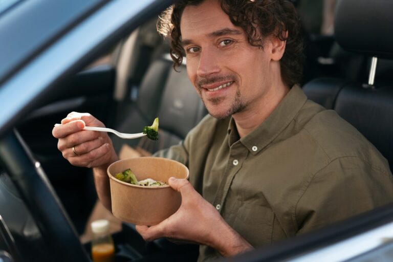 Primer plano de hombre comiendo mientras conduce