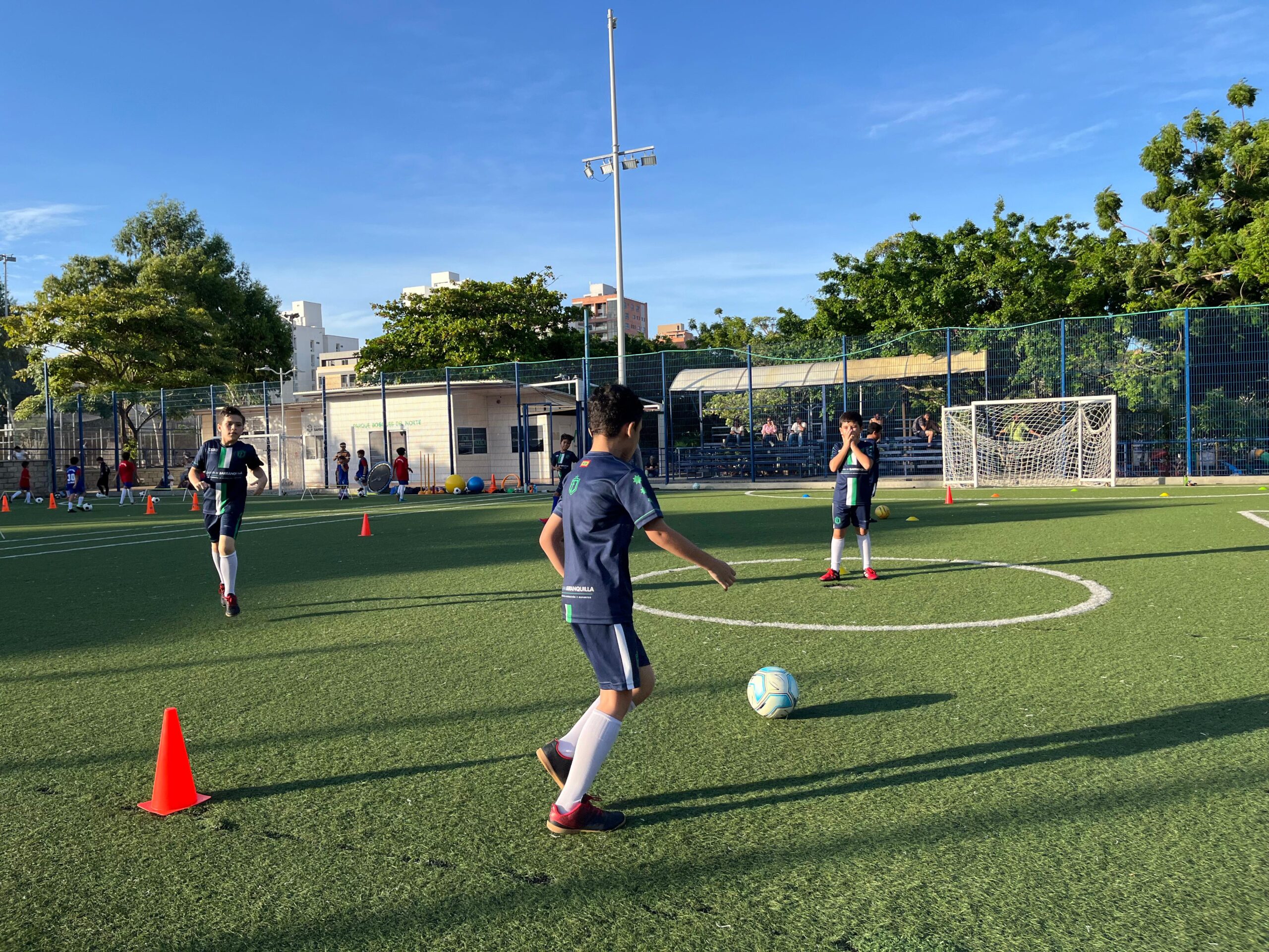 Niños jugando futbol en cancha sintética.