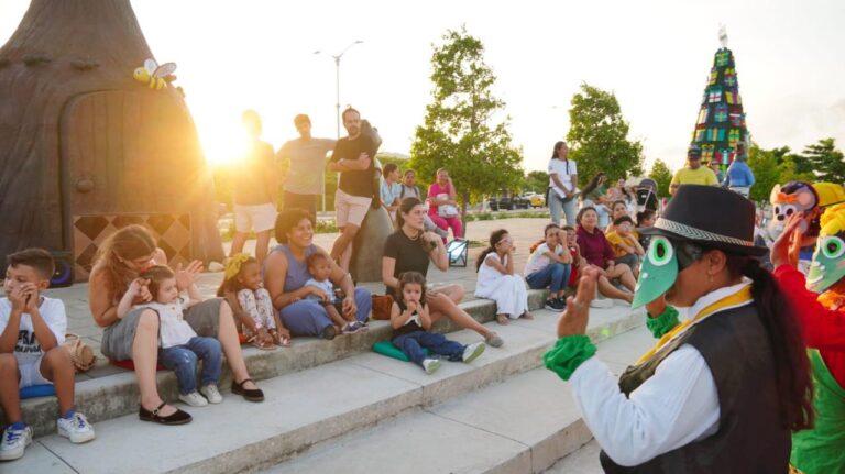 Niños y adultos observan a personas disfrazadas durante una actuación en el Gran Malecón.