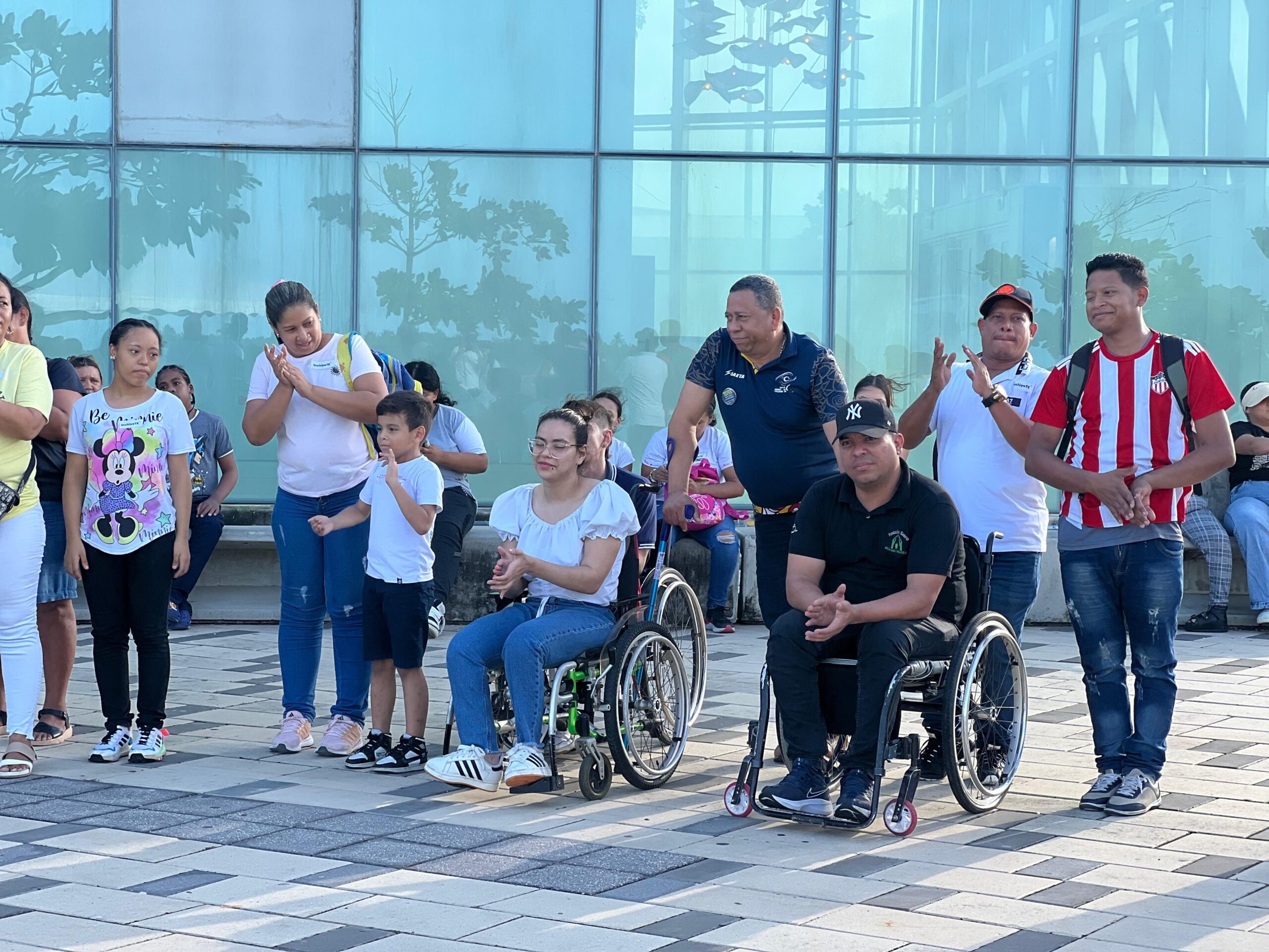 Grupo de personas en sillas de ruedas rodeadas de personas con discapacidad de pie en Gran Malecón.