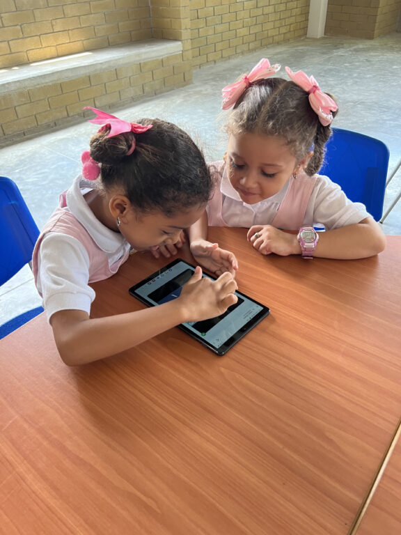 Niñas utilizando tablet en aula de clases.