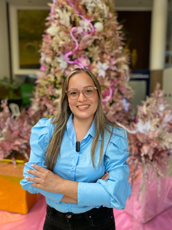 Funcionaria Silvana de la Hoz, sonriendo mientras posa con el árbol de Navidad detrás. 