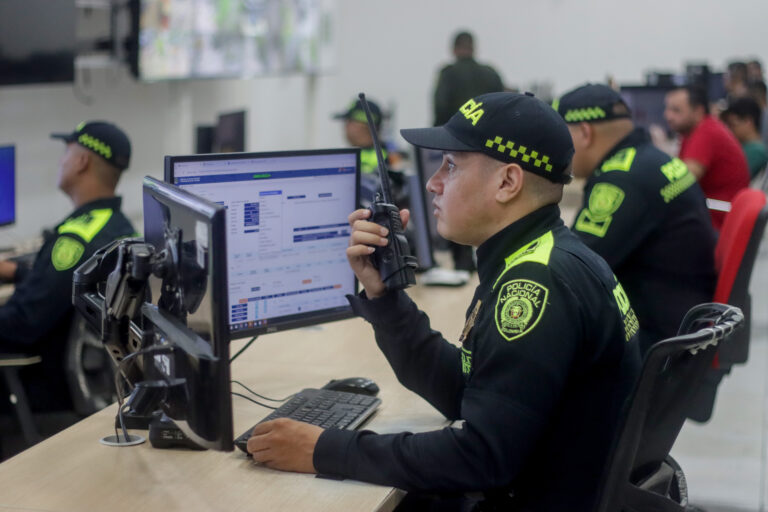 Oficial de policía con radio en mano supervisando videovigilancia en tiempo real.