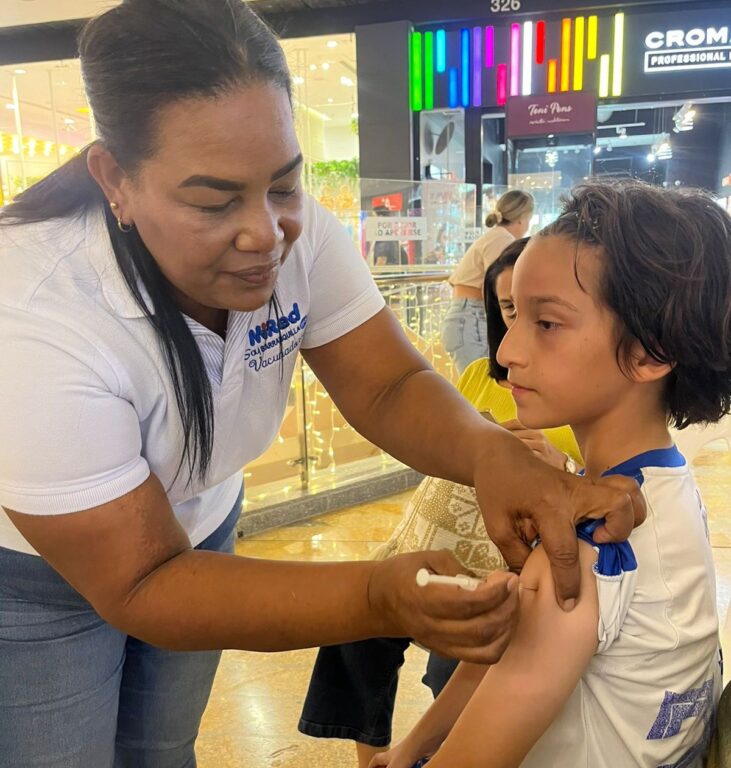 Enfermera realizando vacunación a niño en centro comercial.