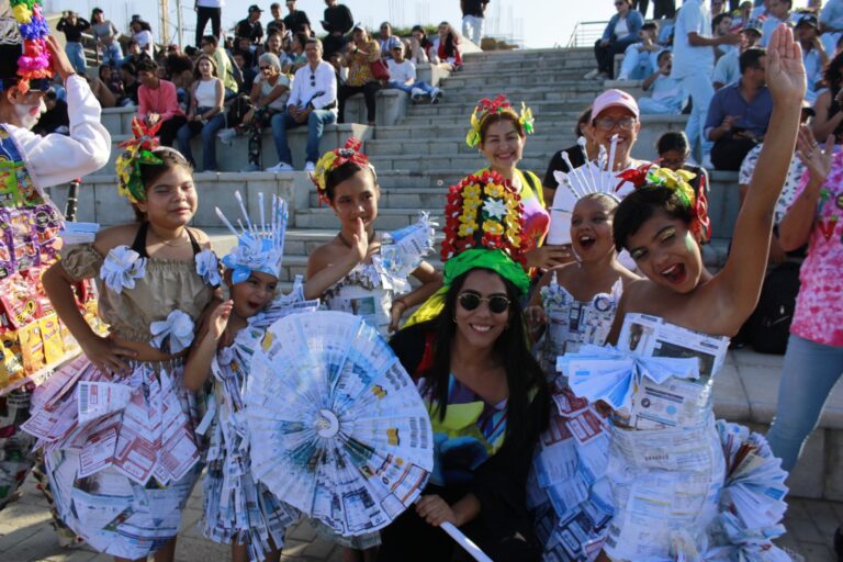 Grupo de niñas sonriendo con vestuarios de material reutilizado en desfile ambiental.