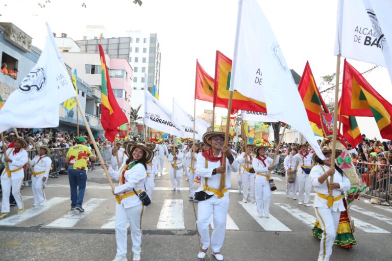 Un grupo de personas levanta las banderas de la Alcaldía de Barranquilla y de la ciudad de Barranquilla.