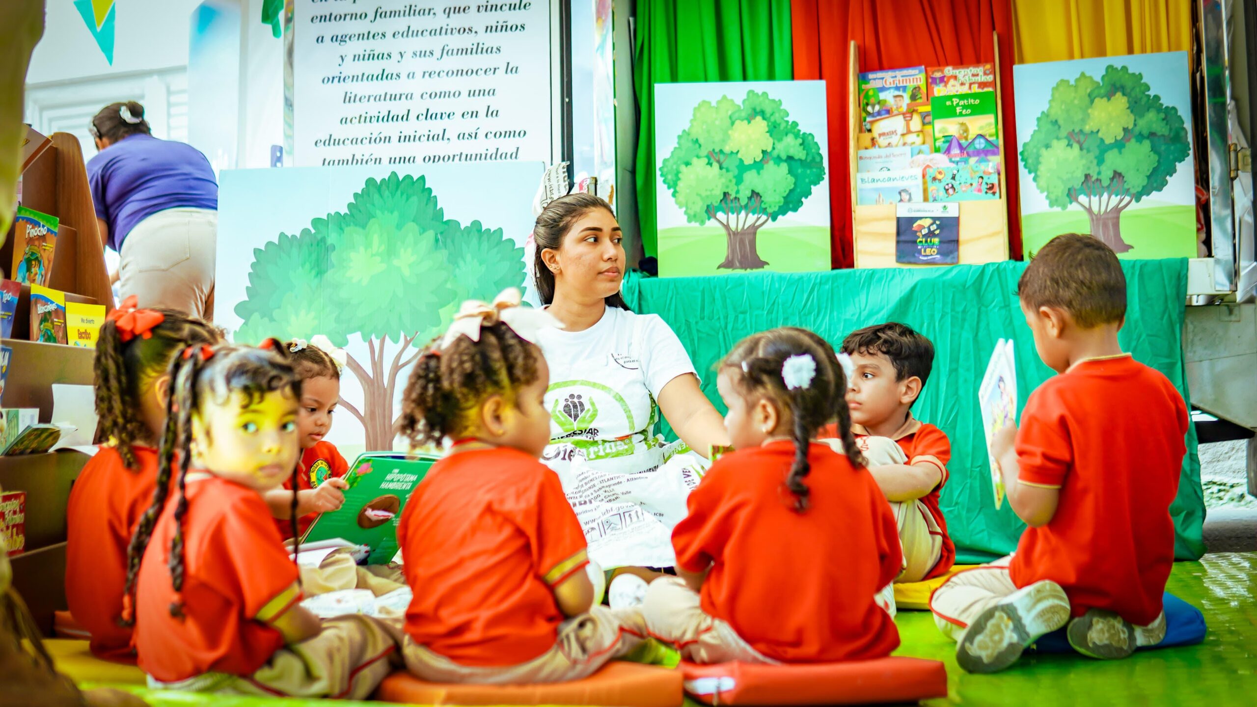 Niños sentados con profesora, participando en actividades del programa de Primera Infancia.