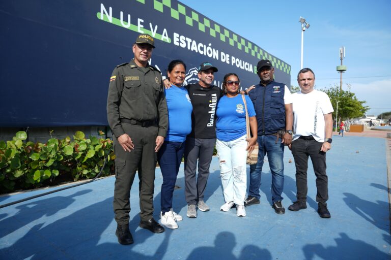 El alcalde Char, Yesid Turbay y otras personas se encuentran de pie frente a la valla informativa de la nueva estación de Policía.