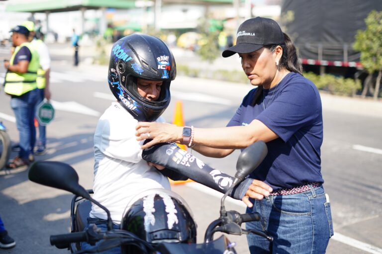 Yaciris Cantillo asiste a un hombre mientras coloca una manga en su motocicleta.