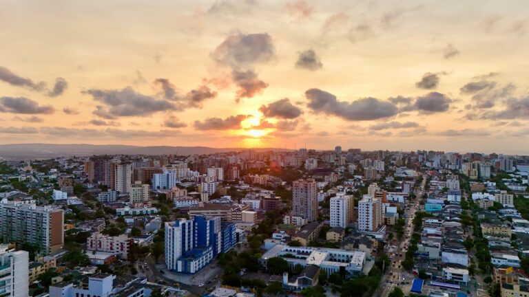 Vista aérea de Barranquilla al atardecer, con edificios y cielo nublado.