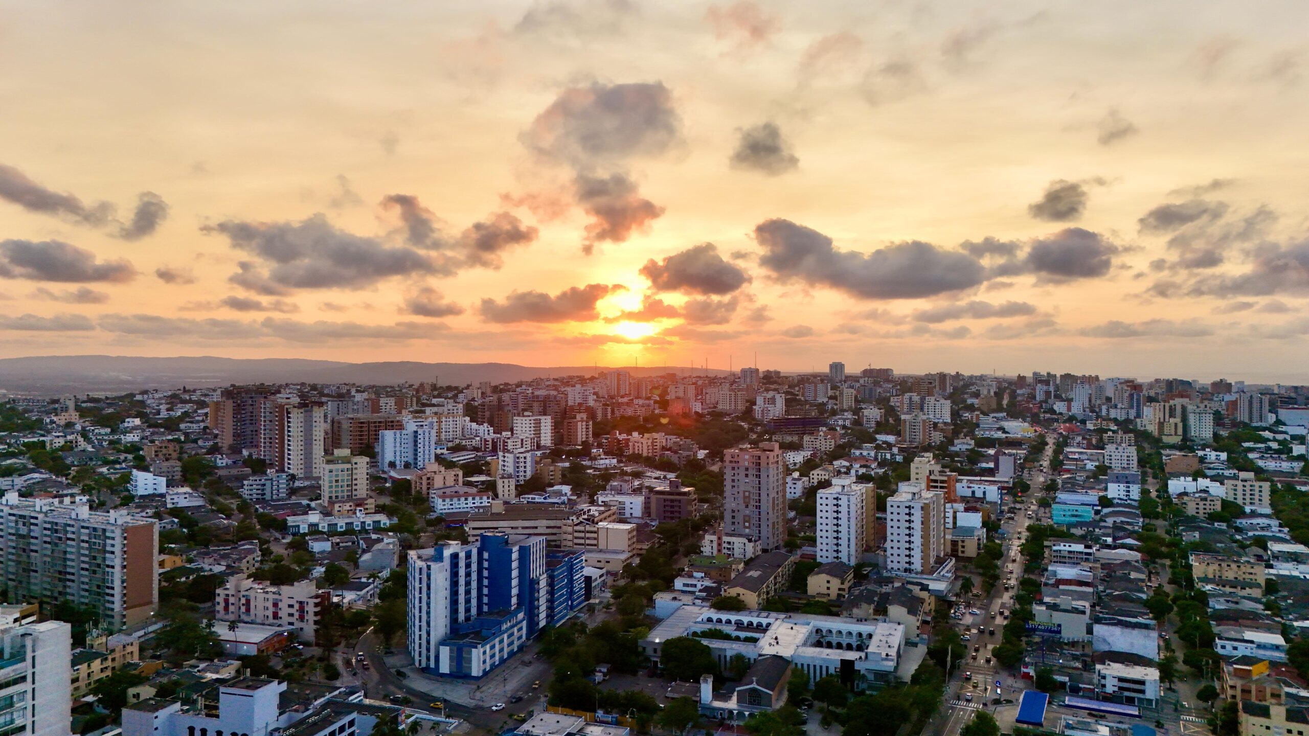 Vista aérea de Barranquilla al atardecer, con edificios y cielo nublado.