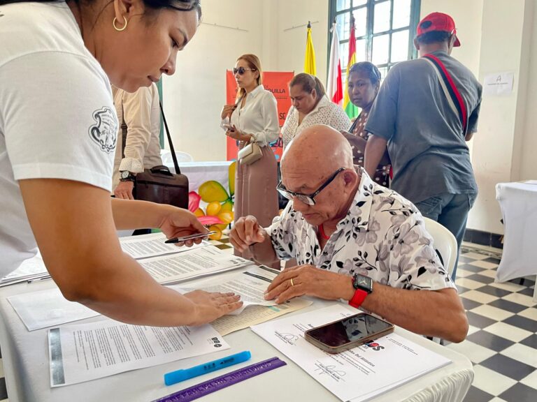 Adulto mayor llena formulario para ahorro voluntario frente a funcionaria.