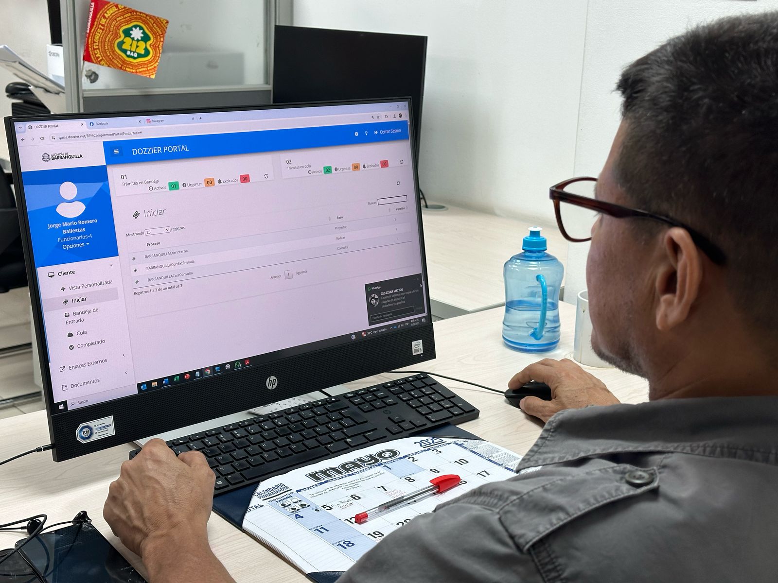 Funcionario de espalda a la camara y de frente a una pantalla de computador.