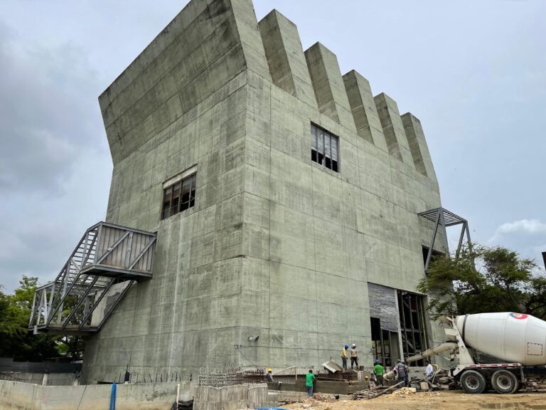 Vista del Museo Moderno de Barranquilla en construcción, con obreros trabajando y maquinaria pesada.