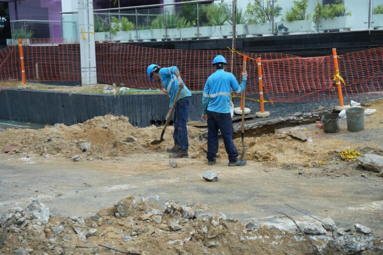 Dos trabajadores con cascos y uniformes ejecutan labores en la obra de la calle 85.
